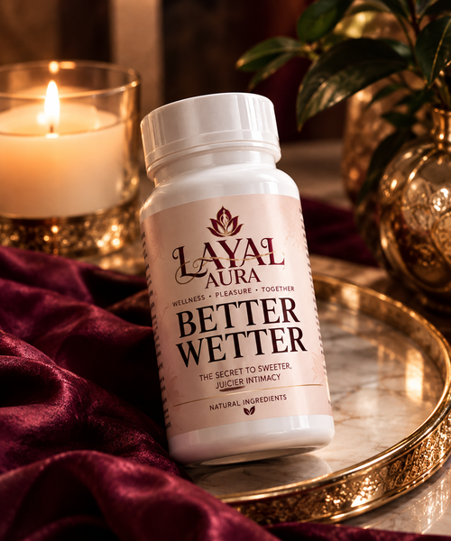 Layal Aura Better Wetter bottle on a gold tray beside a lit candle and burgundy fabric
